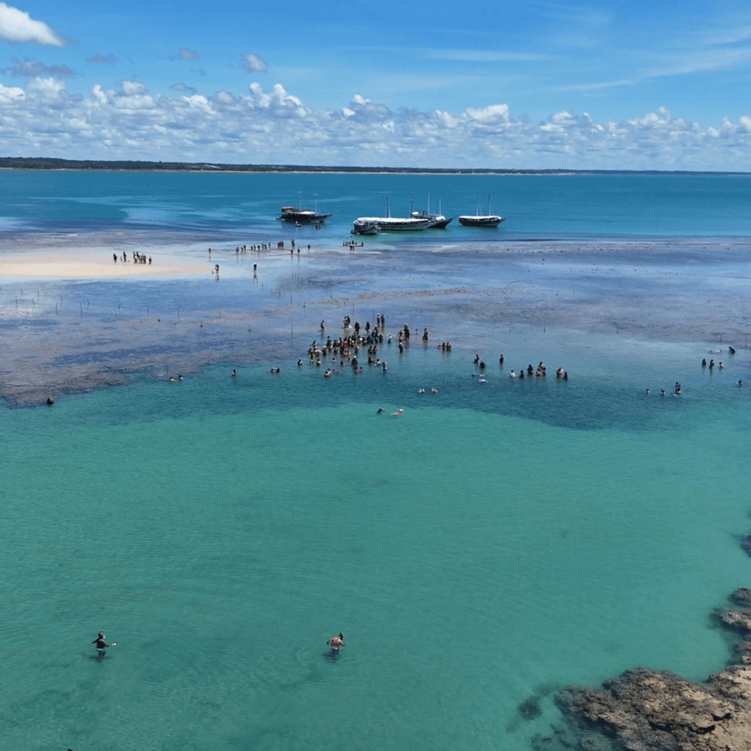 Vista aérea ampla dos recifes com pessoas e barcos.